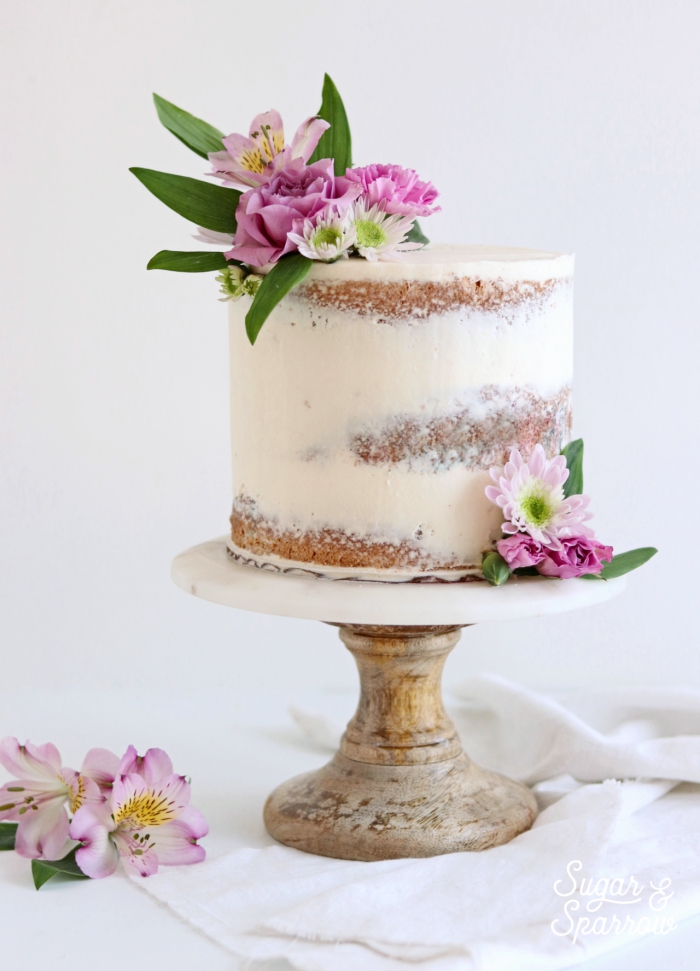 kleine torte dekoriert mit weißer creme, naked cake hochzeitstorte, rosa blüten