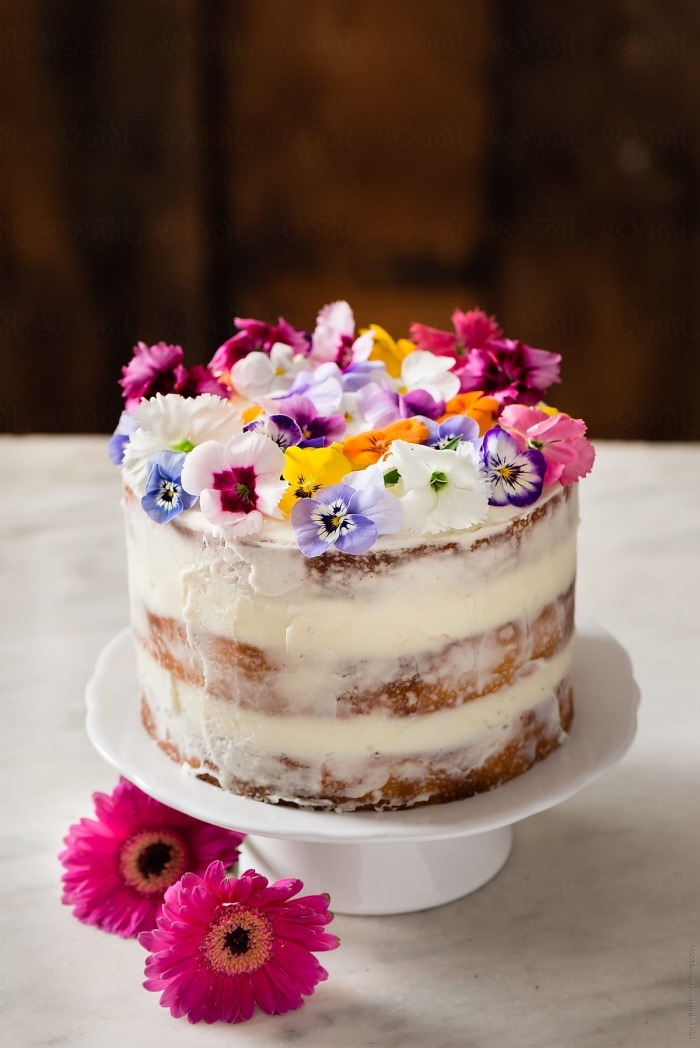 naked cake mit vanille und weiße sahne dekoriert mit kleinen bunten blüten, sommer party essen
