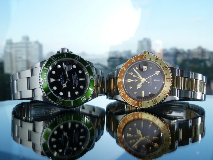 zwei Uhren in grünen und gelben Farben, die Oberfläche widerspiegelt die Uhren, Luxusuhren