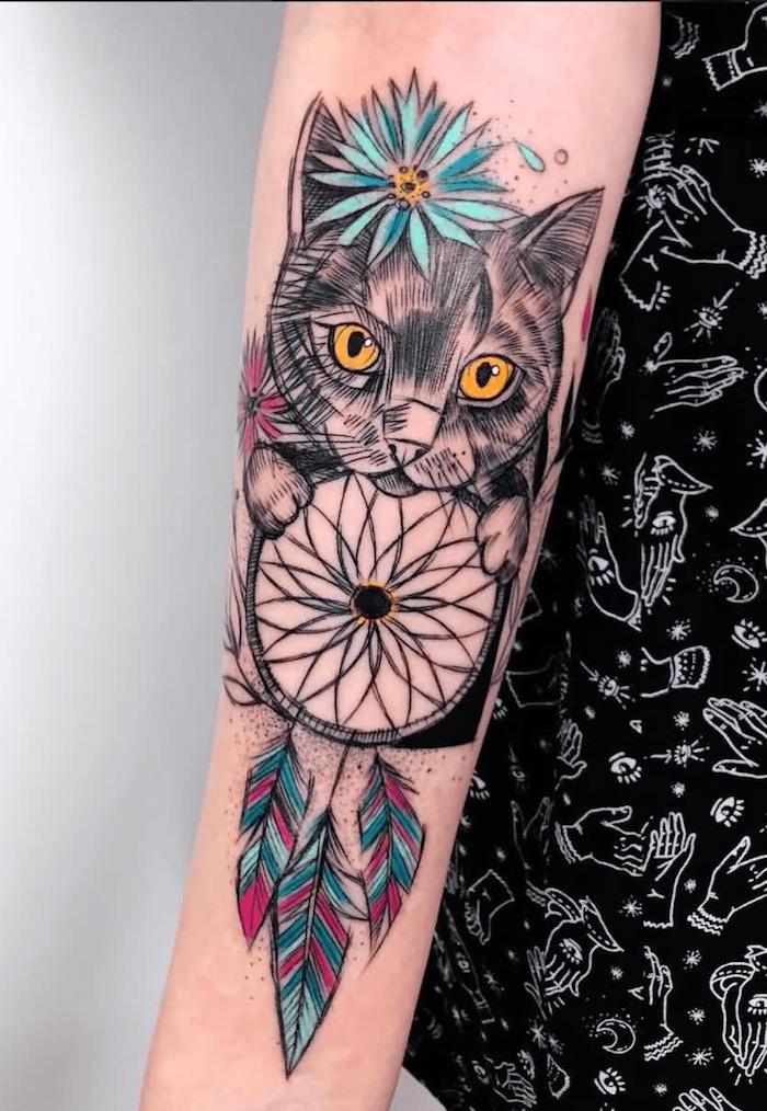 Auffälliges Tattoo am Unterarm, Katze mit blauer Blume, Traumfänger mit lila blauen Federn 