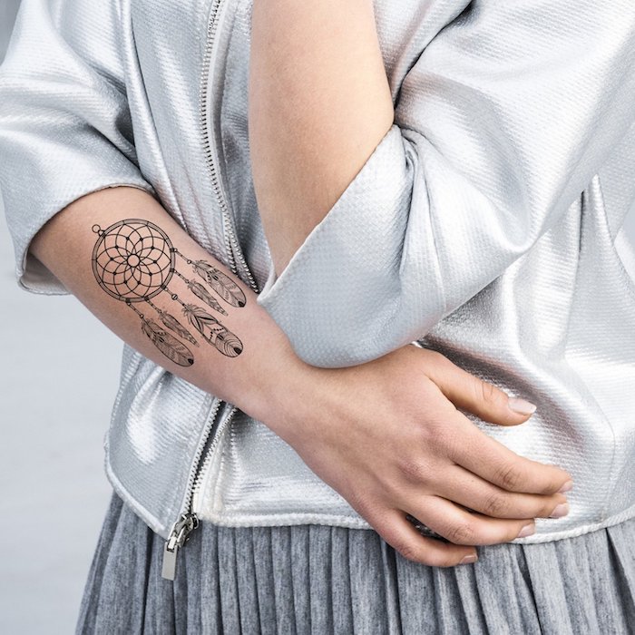 Traumfänger Tattoo am Unterarm, Traumfänger mit Federn, weißer Blazer und grauer Rock 