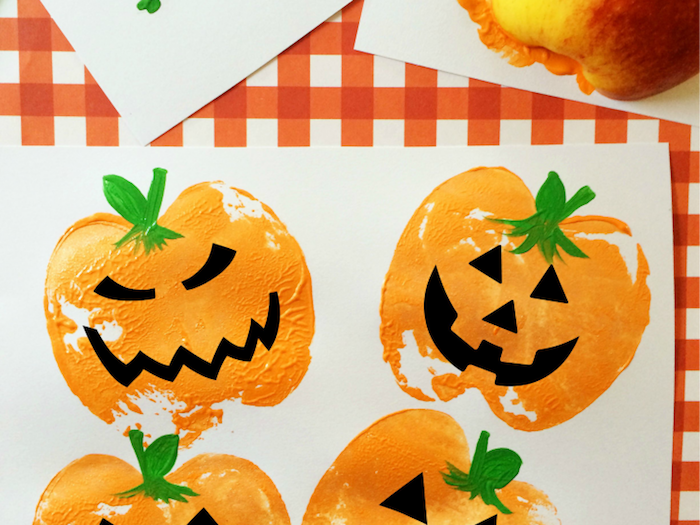 Lustige Halloween Kürbisse malen, Apfel Stempel aufs Papier tupfen, Mund und Augen aus schwarzem Papier schneiden 