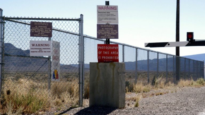 ein verbotenes Foto aus dem Area 51, mit vielen hohen Gras und viele Warnungen