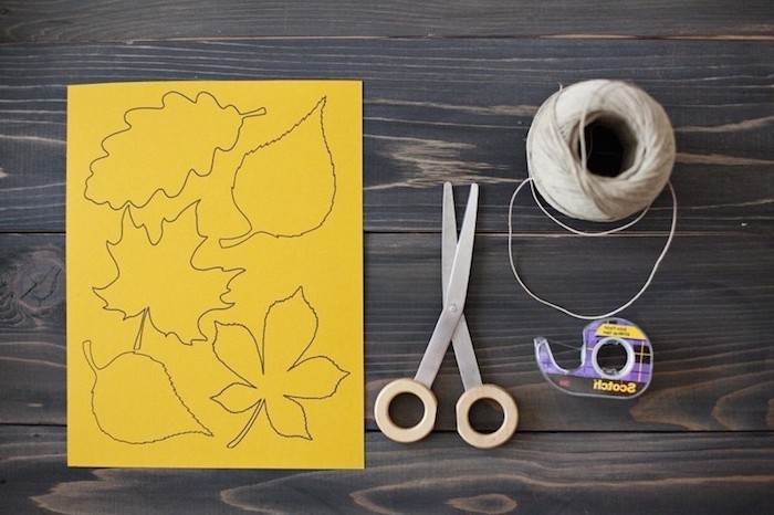 Materialien für DIY herbstliche Girlande, gelbes Papier, Schere und Schnur, Klebeband 