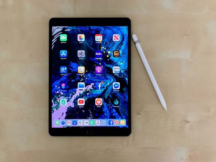 ein iPad mit vielen Apps auf dem Display und ein weißes Apple Pencil