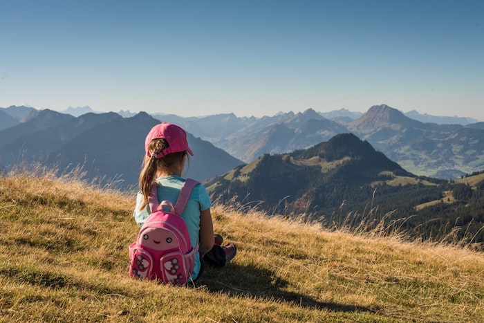 Kleines Mädchen mit blauem T-Shirt und Schmetterling-Schulranzen in Pink 