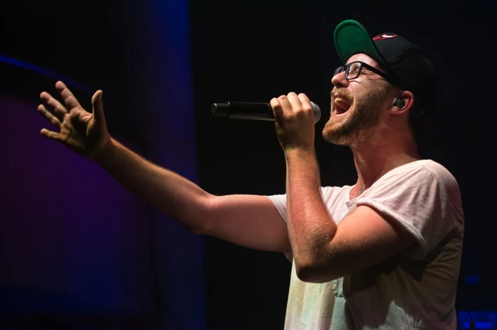 Mark Forster, bei einem Konzert, mit einer weißen Bluse und ein Capp, Brillen mit schwarzen Rahmen