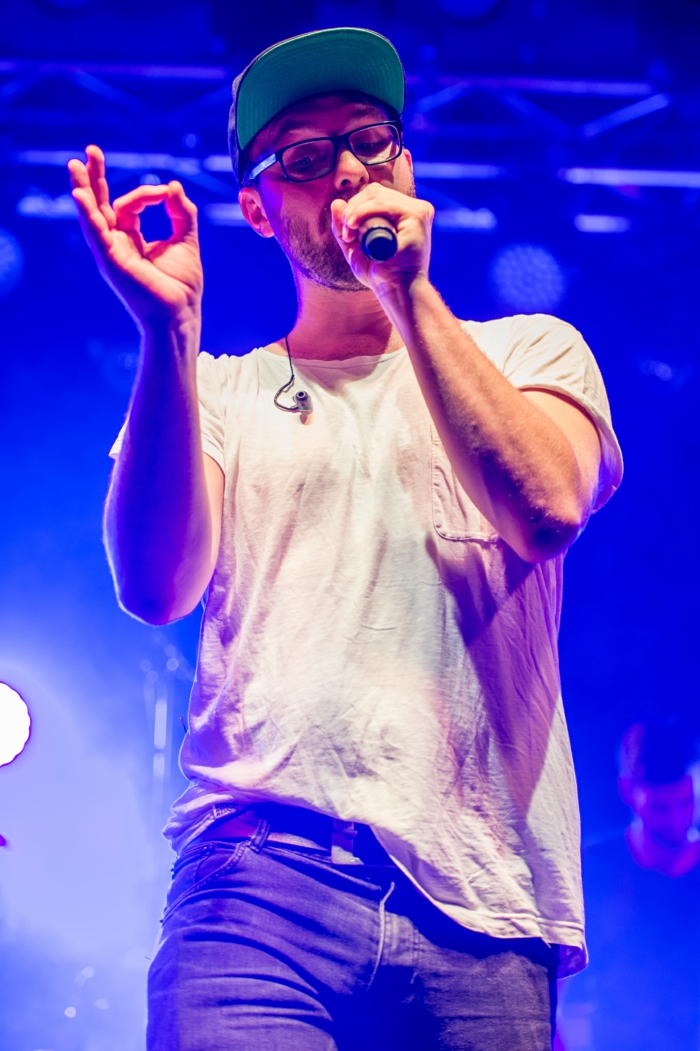 Mark Forster mit einem weißen T-Shirt und ein Microphone, Jeans und brauner Gürtel