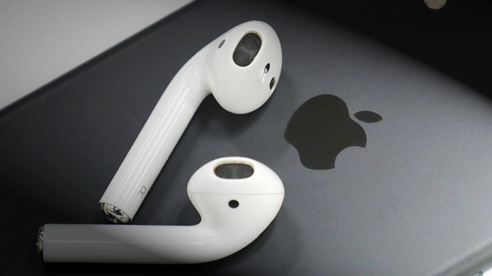 ein graues Smartphone, weiße Kopfhörer, AirPods Pro, ein Logo von Apple