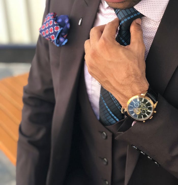 Schwarzer Herrenanzug, weißes Hemd und blaue Krawatte, Armbanduhr mit schwarzem Lederriemen 