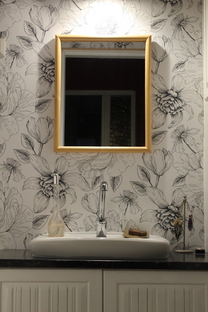 Viereckiger Badspiegel mit goldenem Rahmen, weiße Tapete mit Blumenmuster 