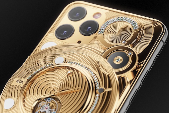 eine uhr aus vielen kleinen goldenen teilen, das handy iphone 11 pro mit drei kameras, ein luxus smartphone