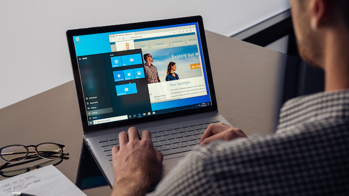 ein mann mit hemd, ein laptop mit dem betriebssystem windows 10 und brille, das neue update für windows 10 