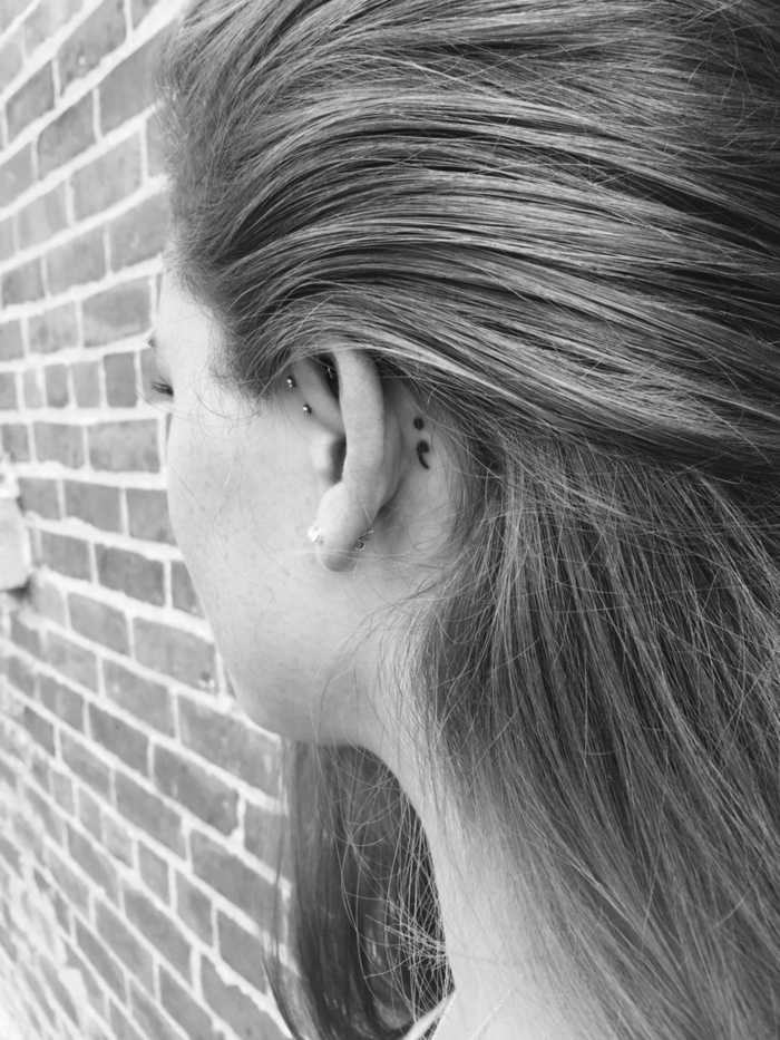 Semicolon Tattoo hinter dem Ohr einer Frau mit Piercing, dunkelblonde Haare, project semicolon, 