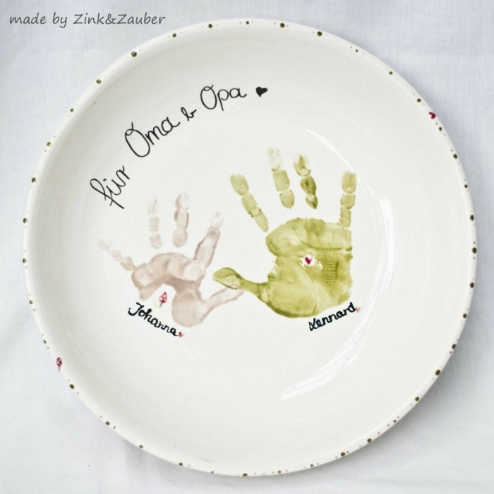Geschenk für Oma basteln, weißer Teller mit Handabdrücken von Kindern, Aufschrift für Oma und Opa