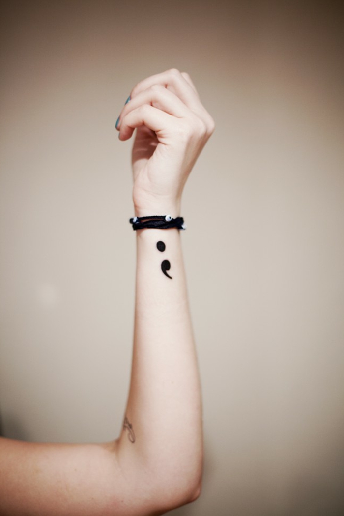 Zarte Hand mit einem Semicolon Tattoo und Armbänder, tattoo psychische störung, heller Hintergrund