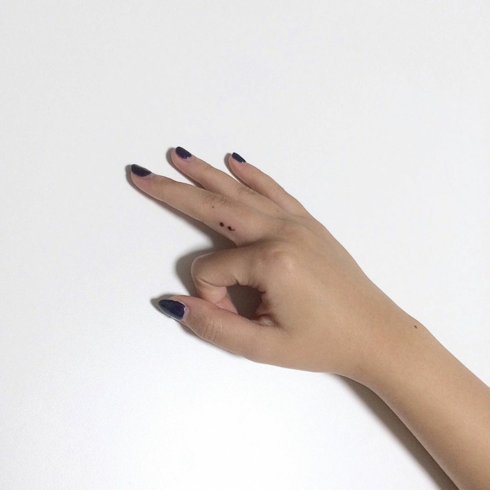 Semicolon Tattoo am Mittelfinger einer Hand mit dunklem Nagellack, tattoo psychische störung, weißer Hintergrund