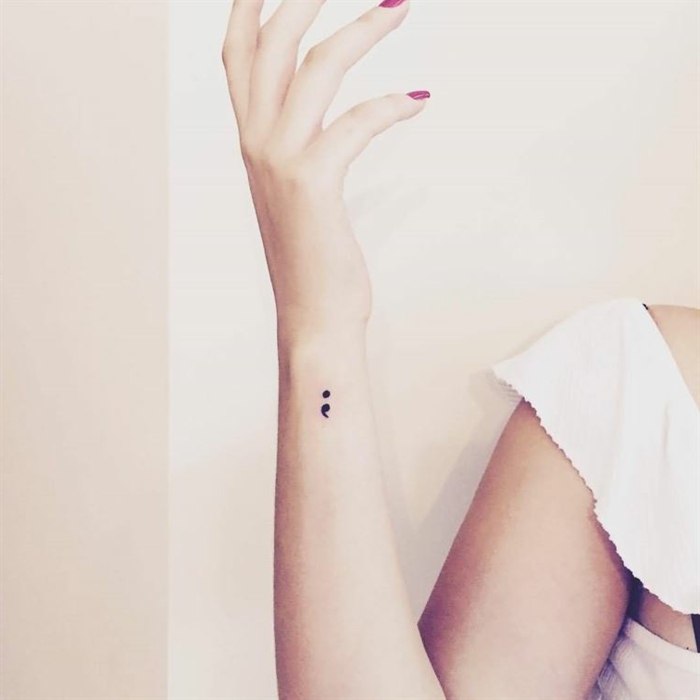 Zärtliche Hand mit pinkem Nagellack und einem kleinen Semicolon Tattoo, tattoo psychische störung