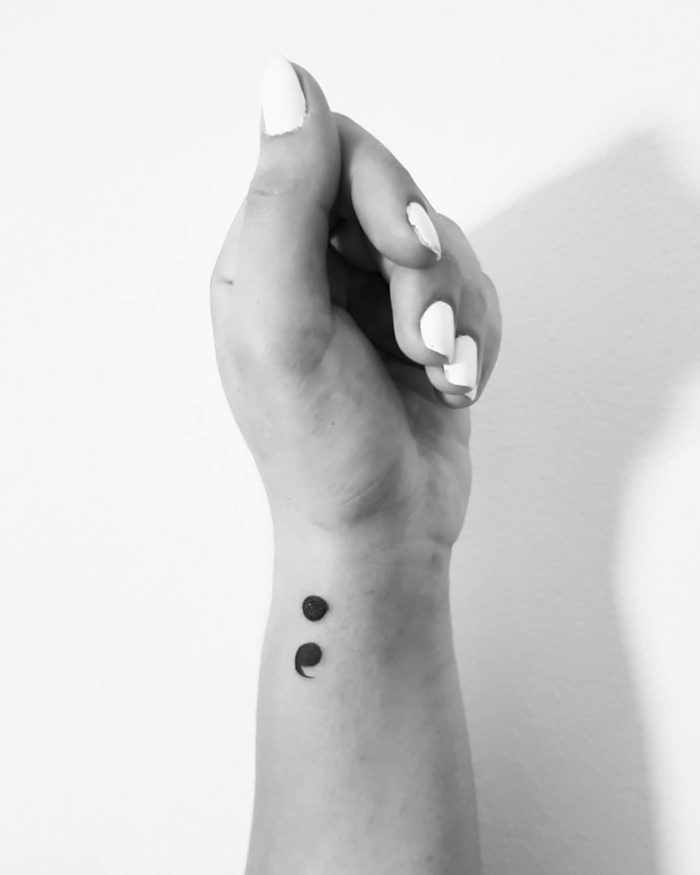 Schwarz-weißes photo von einer Hand mit einem Semicolon Tattoo, zeichen für depression, weißer Nagellack