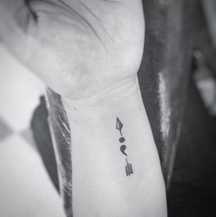 Tattoo Semicolon und ein nach oben zeigender Pfeil am Arm, semikolon tattoo bedeutung, schwarz-weiß