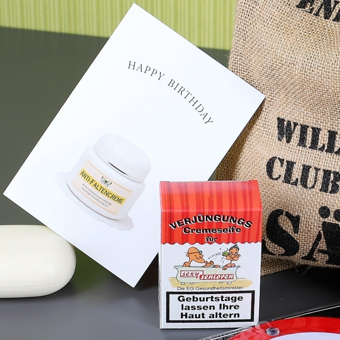 Seife in einer Zigarettenschachtel, mit lustiger Beschriftung, Abbild von Senioren in der Badewanne, Geburtstagskarte mit Abbild von Anti-Faltencreme