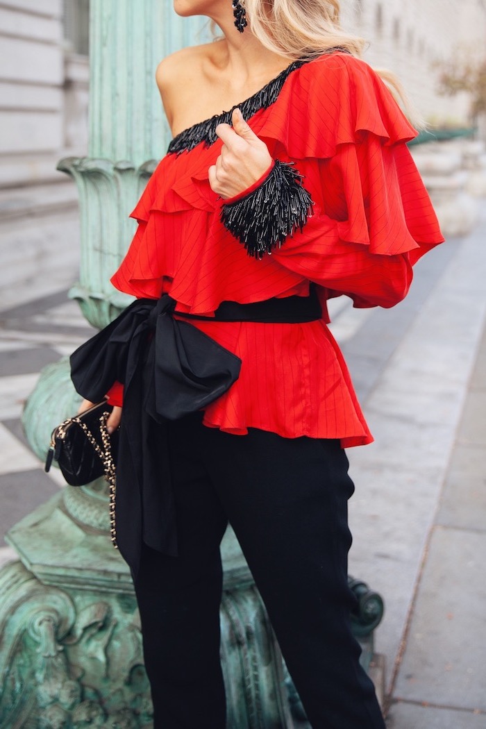 Outfit Idee für Silvester, rotes Top mit einem Ärmel, große schwarze Schleife, schwarze Hose 