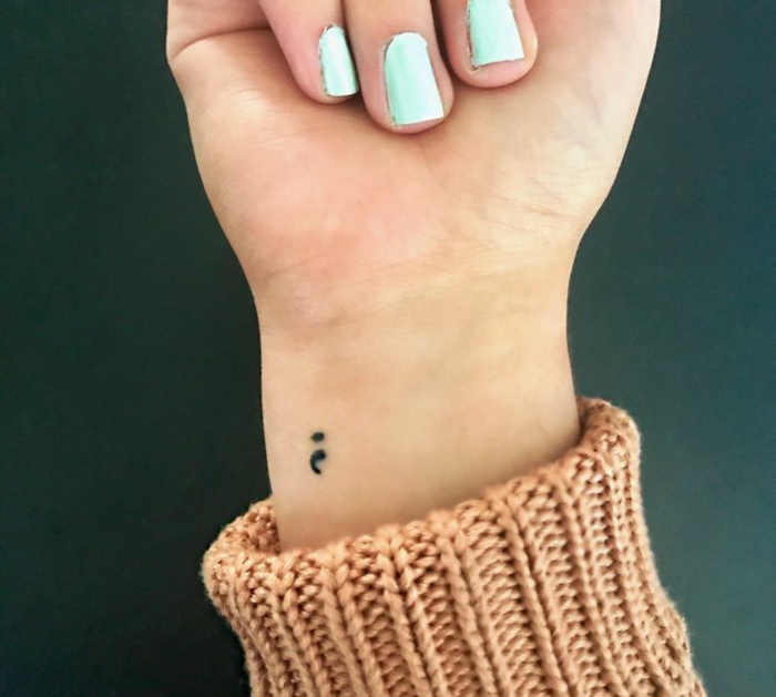 Kleines Semicolon Tattoo am Arm einer Frau mit bläulichem Nagellack, semikolon tattoo bedeutung