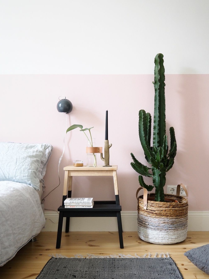 Wand bemalt in zwei Farben, Schlafzimmer rosa grau, Teppich und Lampe in grau, großer Kaktus als Dekoration in einem Weidenkorb
