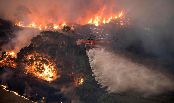 ein großer oranger fliegender hubschrauber und wasser, die buschbrände in australien, ein wald und feuer