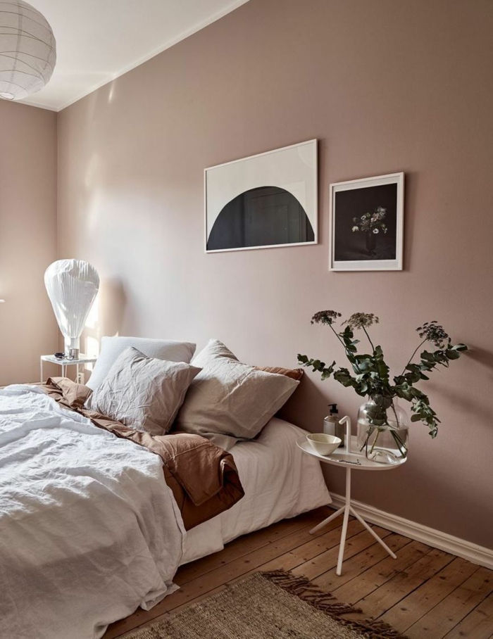 Aktuelle Wohnraumfarben fürs Schlafzimmer, Wandfarbe altrosa, Bett mit Bettwäsche in beige, schwarz weiße Bilder an die Wand. runder Tisch, 