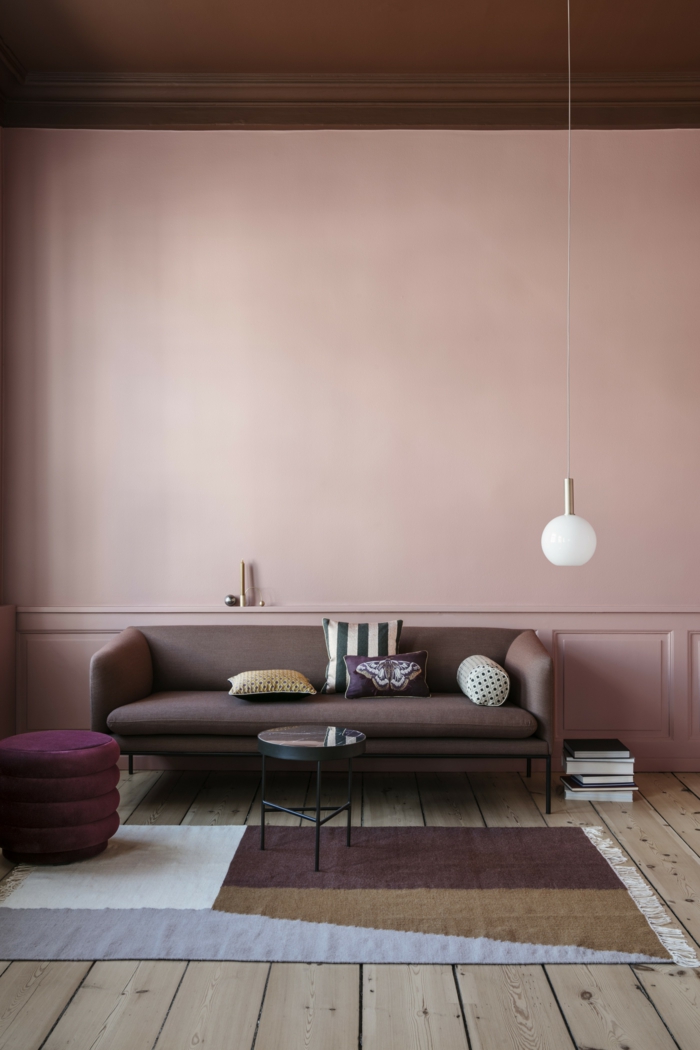 rosa Farbe, Grafischer Teppich in verschiedenen Farben, dunkler Couch, Wandfarbe Inspiration in altrosa, Hängende Lampe, Boden aus Holz,