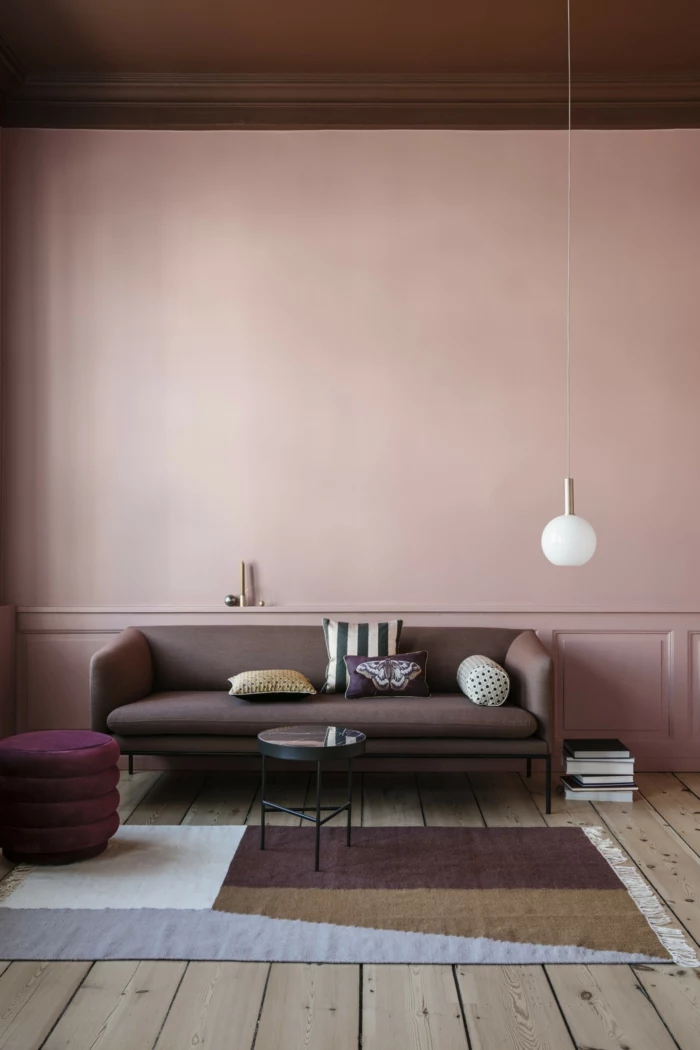 rosa Farbe, Grafischer Teppich in verschiedenen Farben, dunkler Couch, Wandfarbe Inspiration in altrosa, Hängende Lampe, Boden aus Holz,