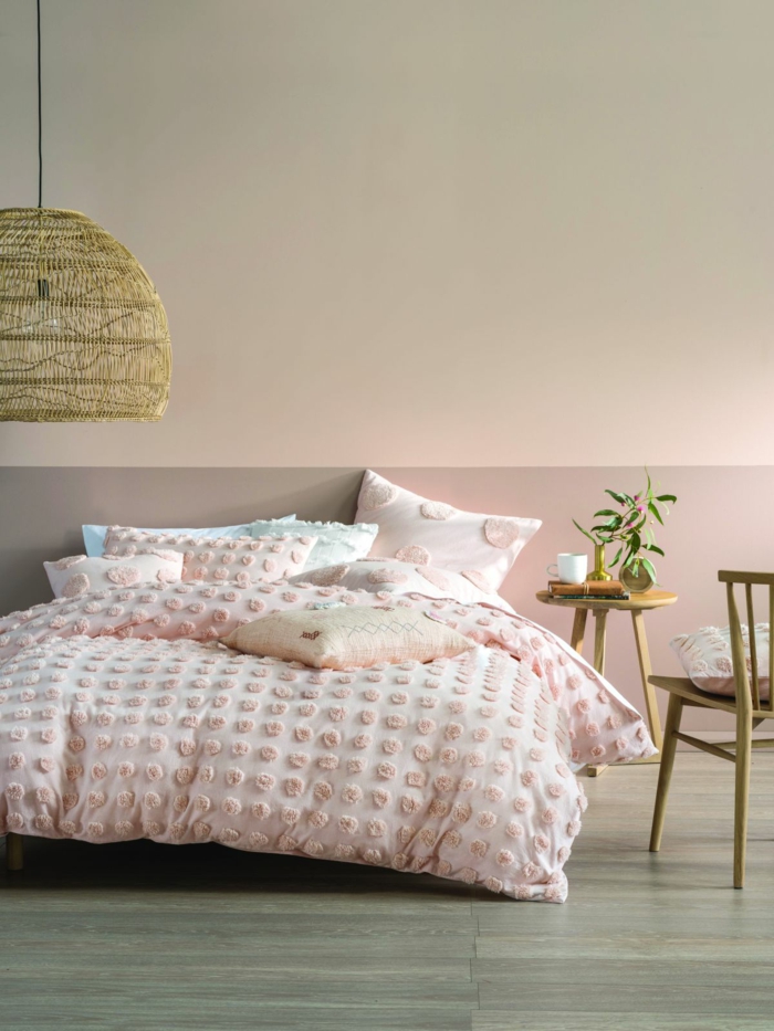 Schlafzimmer rosa grau, Colour-Blocking Wand, großes Bett mit Bettwäsche in rosa Farbe, runder Tisch und Stuhl aus Holz