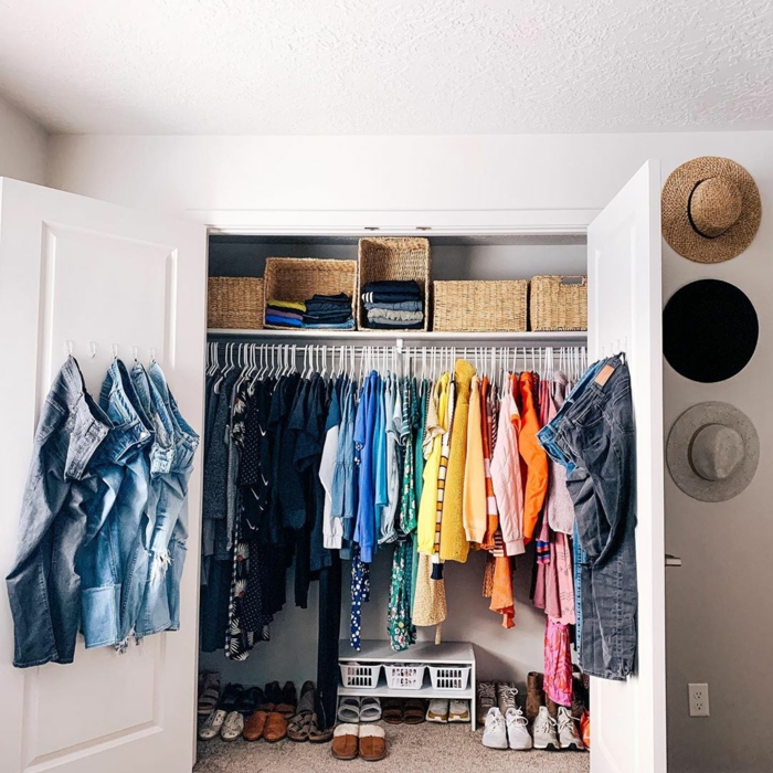 Anordnung kleiner Kleiderschrank nach Farben, Ankleidezimmer kleiner Raum, geschlossener Schrank, aufgehängte Jeans an die Tür, 