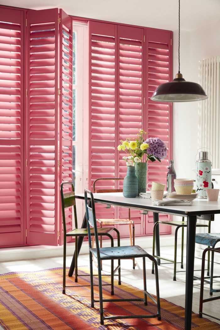 Inneneinrichtung einer kleinen Küche mit Jalousien in pink, kleiner Tisch mit Stühle, bunter Teppich, Aktuelle Wohnraumfarben