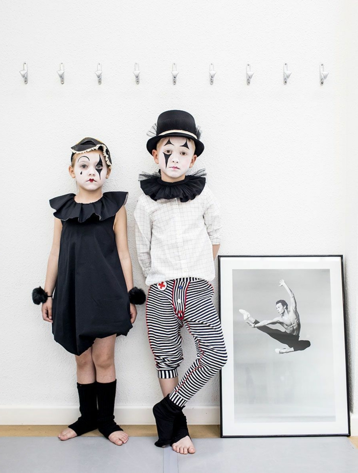 Kinderkostüme Fasching, Arlequino Kostüm, Mädchen im schwarzen Kleid und weiß und schwarz geschminktes Gesicht, Junge in schwarz-weiß karierte Hose und weißes T-Shirt