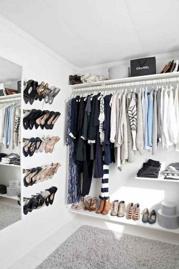Schuhe aufgehängt an die Wand, offener Kleiderschrank mit Kleiderstange, Klamotten angeordnet nach Farbe, grauer Teppich
