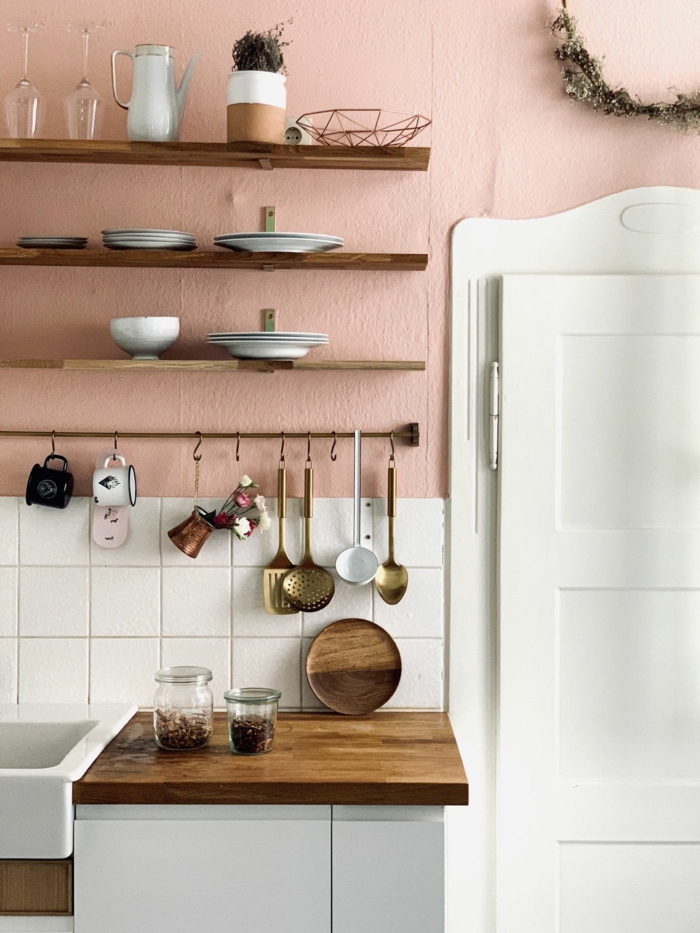 Ausstattung einer Küche in Wandfarbe altrosa und weiße Fliesen, Tischplatte aus Holz, weiße Tür, Wandfarbe Inspiration, 