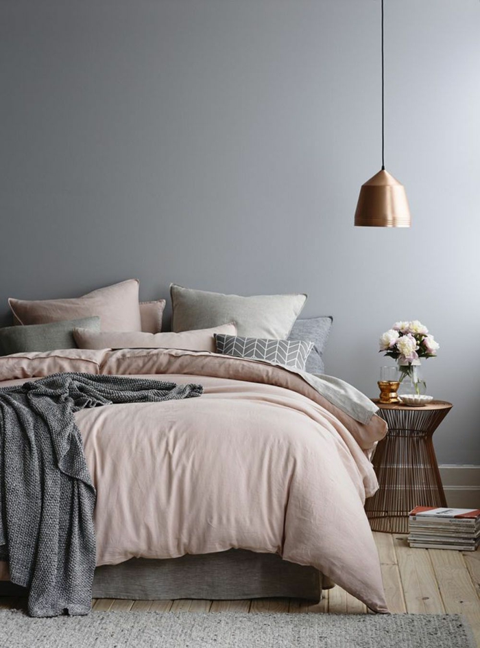 Schlafzimmer rosa grau, Pendelleuchte in gold-rosa Farbe, altrosa Bettwäsche und graue Kissen, Korbtisch mit Blumen obendrauf