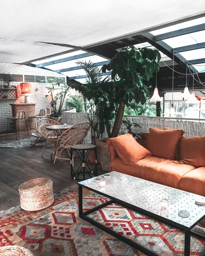 Bohemisches Wohnzimmer mit große grüne Pflanze, Sofa in Orange, bunter geometrischer Teppich