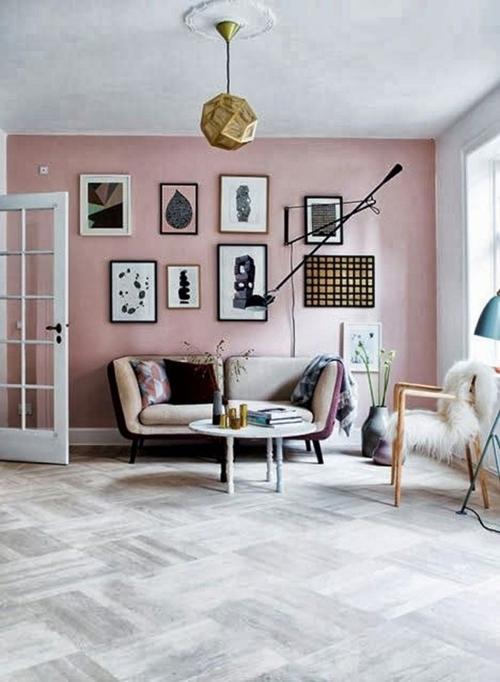 Wohnzimmer grau rosa, Wandfarbe Inspiration, große Wand mit aufgehängten Bildern, kleiner Couch in beige, Stuhl mit flauschiger Decke 