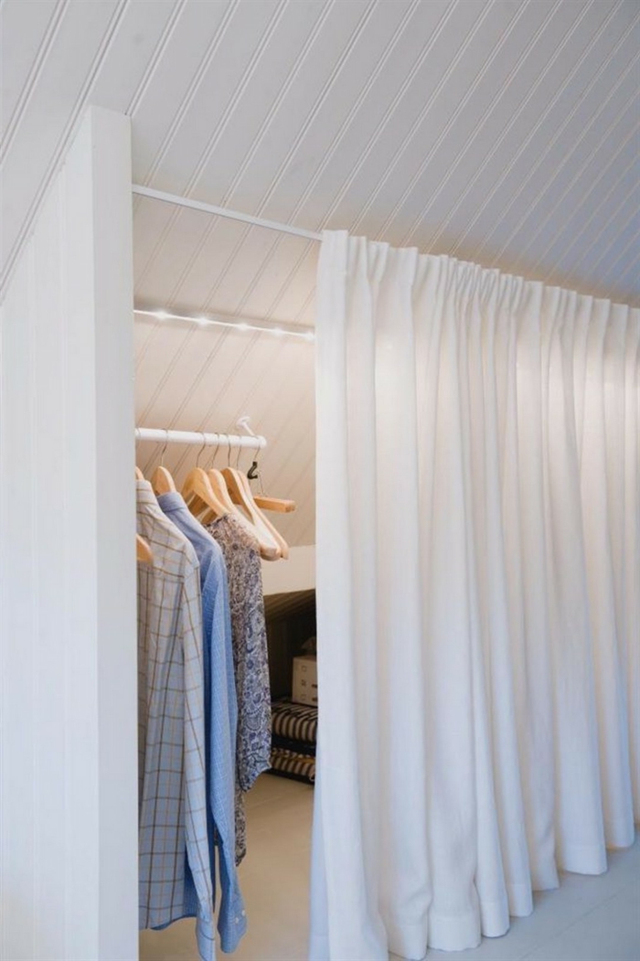 Begehbarer Kleiderschrank Dachschräge Vorhang in weiß und kleine Lampen, Klamotten an Kleiderstange