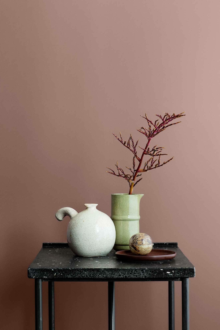 Schlafzimmer altrosa, schwarzer Tisch mit Dekoration, Vase in hellgrün und Teekanne in weiß, rosa Farbe