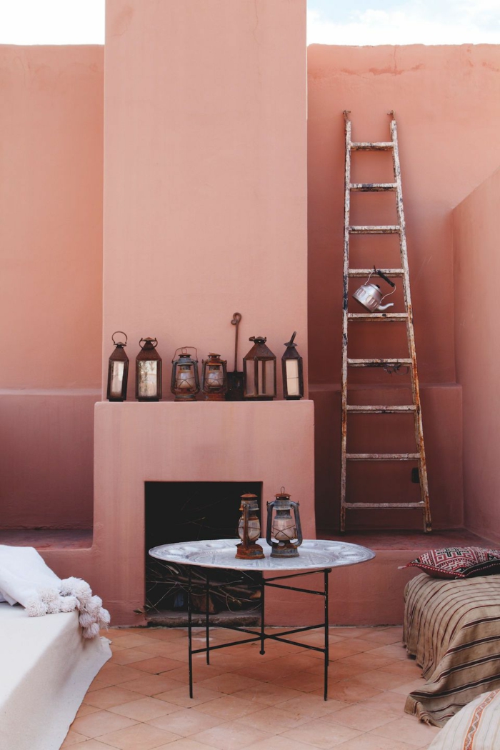 viele Laternen als Dekoration, eine Leiter, runder Tisch mit dünnen Beinen, weißer Couch, pastell rosa Wandfarbe