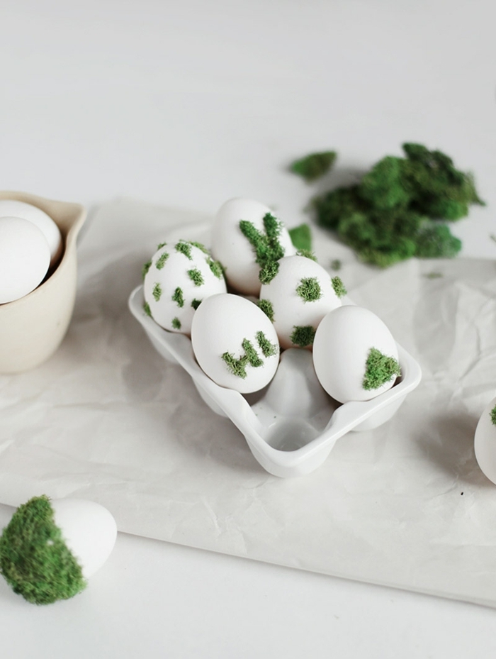 Dekorierte weiße Eier mit grünem Moos, Bastelideen zu Ostern, weiße Eier in einer Eierschale. Idee für Osterdekoration