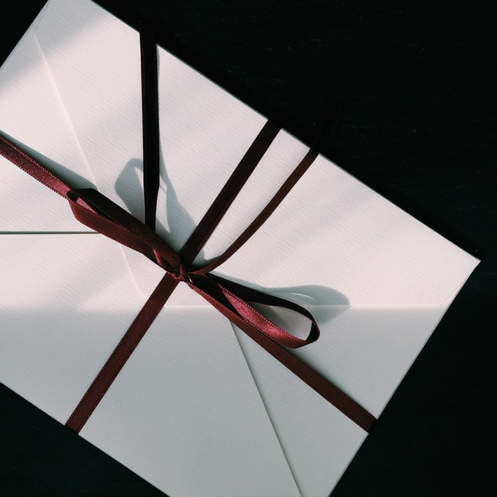 eleganter weißer Briefumschlag mit rotem Band, wichtige Verwendung der Briefumschläge im täglichen Leben