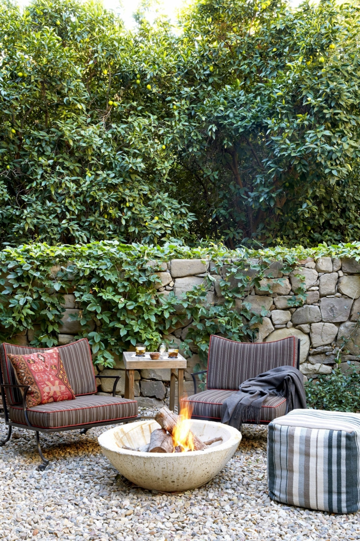 Garten Einrichtung mit einer Feuerstelle aus stein, pinterest Garten, Sichtschutz aus Steinen, zwei dunkelbraune Sessel, große Bäume