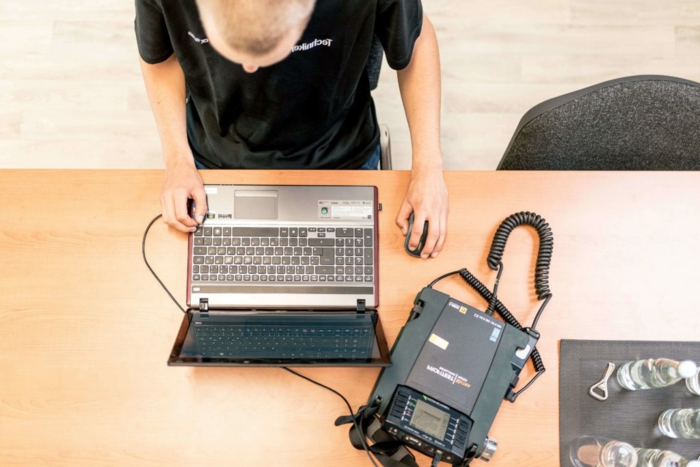 Prüfung ortsveränderlicher elektrischer Betriebsmittel, DGUV V3 Vorschrift, Mann prüft Laptop mit einem Gerät