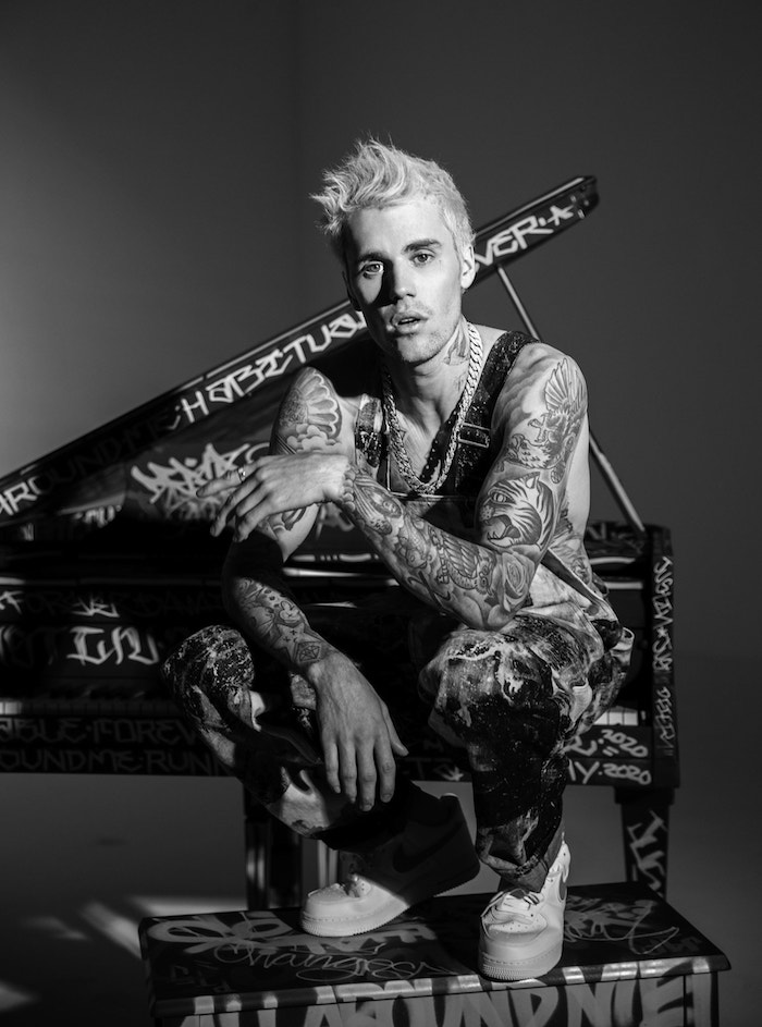 mann mit vielen tattoos und langen halsketten, ein schwarz weißes. bild mit dem pop sänger Justin Bieber