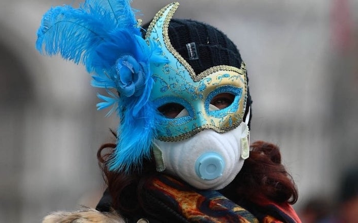 der karneval un venedig, eine frau mit maske mit langen blauen federn, der diesjährige karneval in venedig wird wegen coronavirus beenden